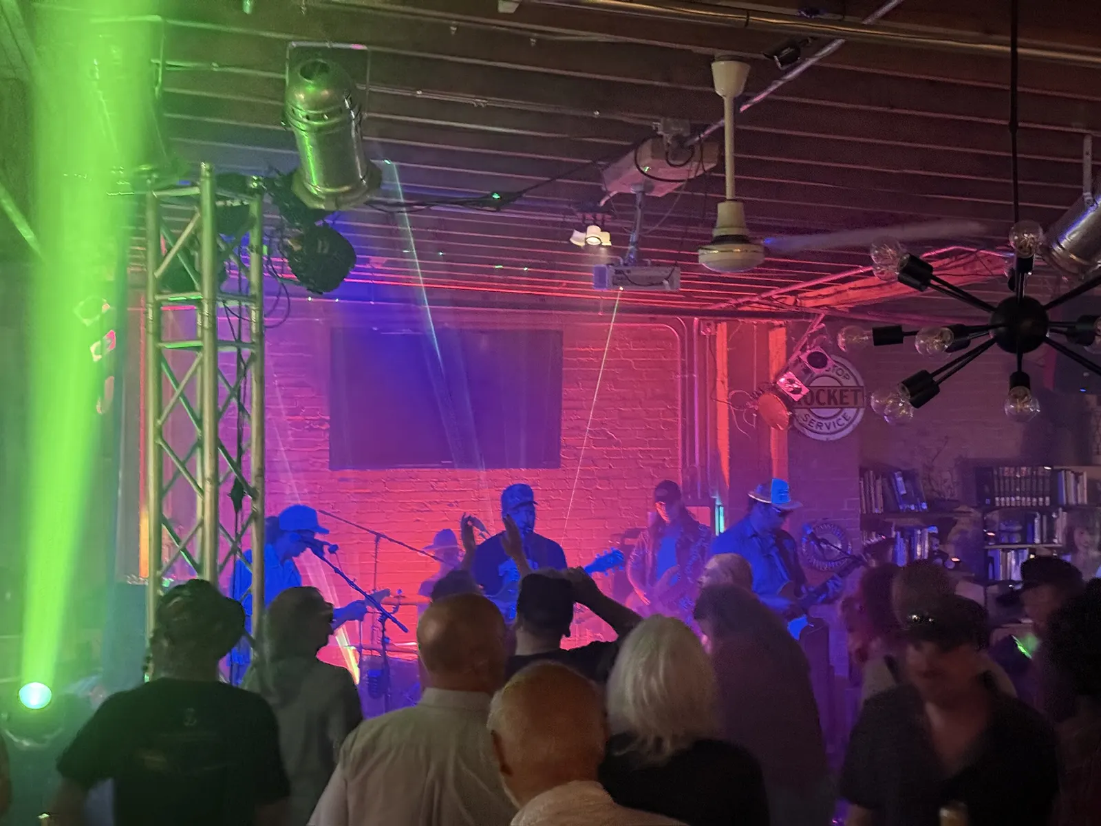 Crowd facing a live band lit in green and blue